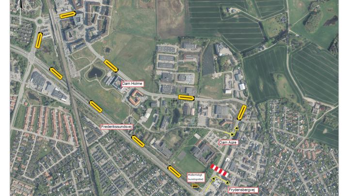 Dette er et kort over en by, der viser veje som 'Dam Holme', 'Frederikssundsvej', 'Dam Agre' og 'Frydensbergvej', med en specifik markering for et midlertidigt busstoppested. Kortet stammer fra GeoDanmark og Styrelsen for Dataforsyning og Infrastruktur.