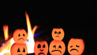 seks jack-o-lanterne græskar sidder ved et bål med triste ansigter