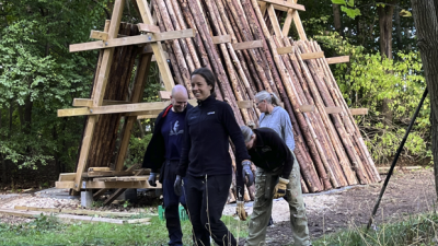 En gruppe af fire går smilende væk fra en raftegård fylt med rafter
